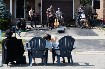 kids sitting on chairs watching musician perform on front porch
