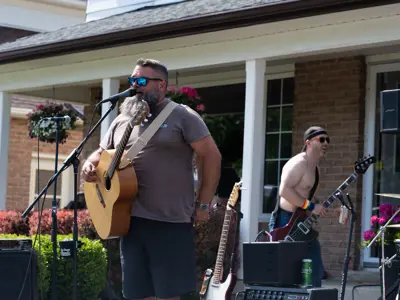 man with acoustic guitar performing in front of crowd outside