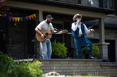 two men with acoustic guitars performing on a porch